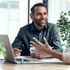 A businessman smiles as he speaks with a customer.  